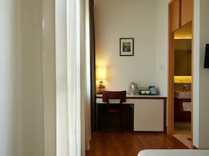 Una habitación funcional con escritorio, silla y una pequeña cocina.