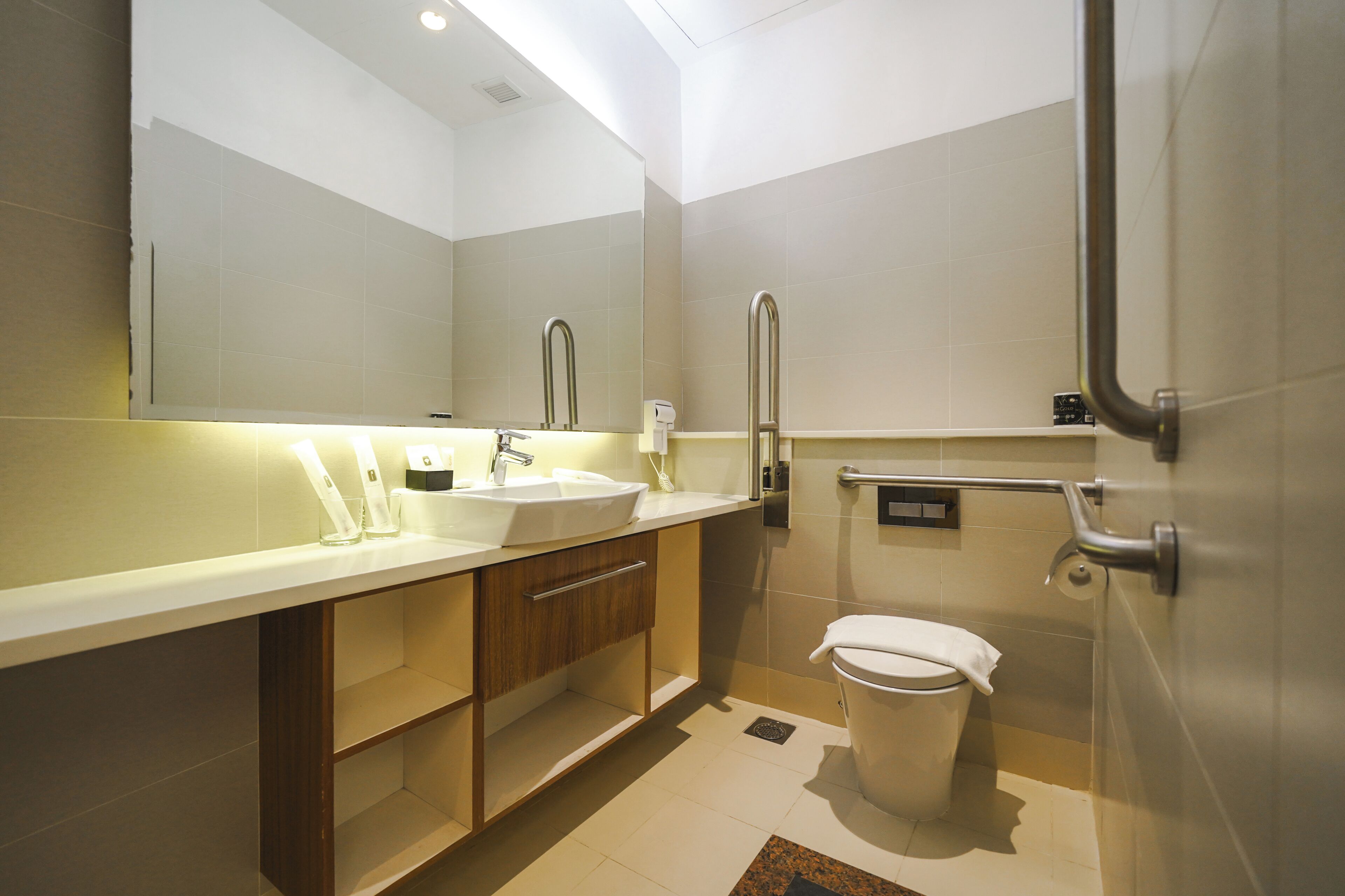 Une salle de bain moderne avec un grand miroir, un lavabo, des toilettes et un espace douche.