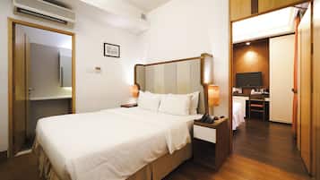 Una habitación de hotel con cama, lámparas de noche, televisor y un armario de madera.