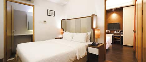 Una habitación de hotel con cama, lámparas de noche, televisor y un armario de madera.