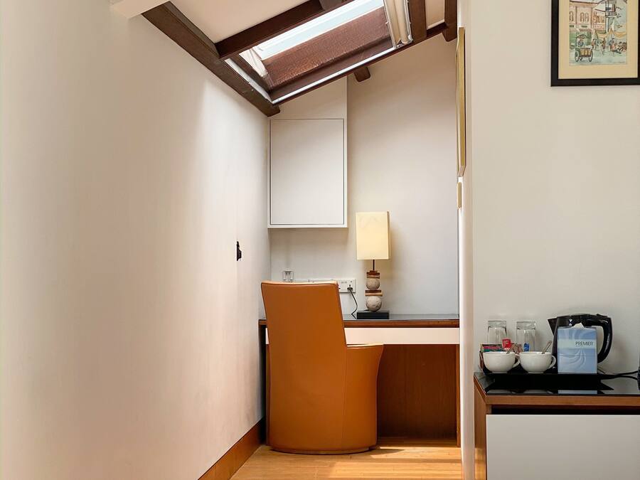 Una habitación de hotel con cama, escritorio, silla, lámpara y cafetera.