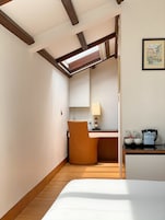 A hotel room with a bed, a desk with a chair, a lamp, and a coffee maker.