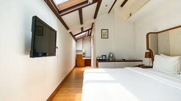 A hotel room with a bed, a desk, a chair, a television, and a skylight.