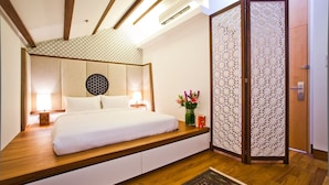 A modern bedroom with a bed, bedside lamps, a decorative wall panel, and a wooden floor.