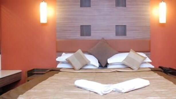 Ein Hotelzimmer mit Bett, Kissen, einem ordentlich gefalteten Handtuch und zwei Wandleuchten.