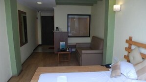 Ein Hotelzimmer mit einem Bett, einem Schreibtisch, einem Sessel und einem Fernseher.