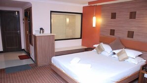 Ein Hotelzimmer mit einem großen Bett, einem kleinen Schreibtisch, einem Fenster und einer Tür.