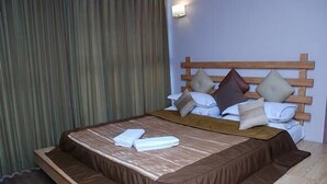Ein Hotelzimmer mit einem Bett, einem Holzkopfteil und einem Vorhang.