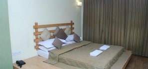 A neatly made bed with a wooden headboard, pillows, and a blanket.