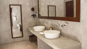 A modern bathroom with two large white sinks, a large mirror, and a towel rack.