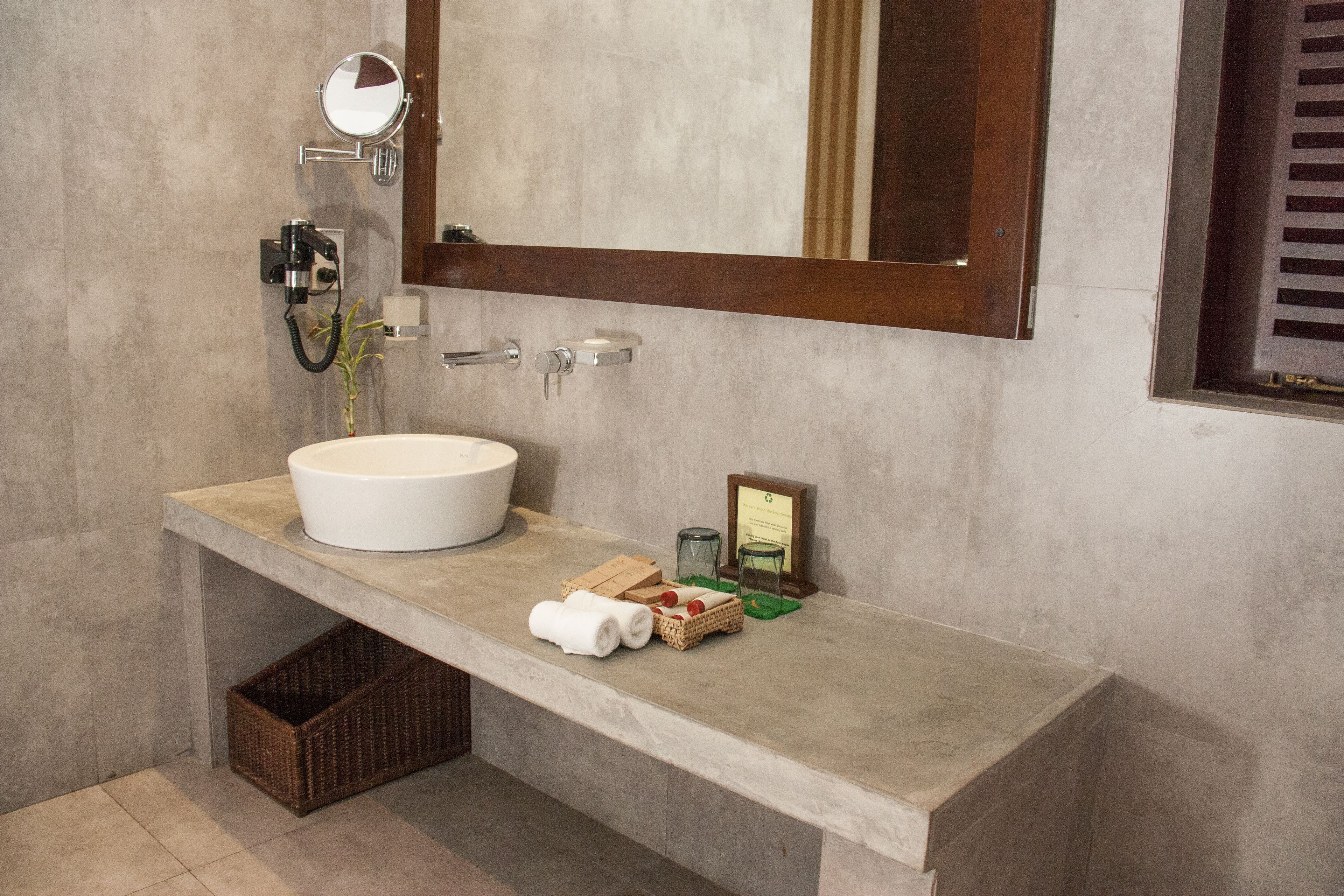 A bathroom with a large white sink, a mirror, a towel rack, and a small framed certificate on the countertop.