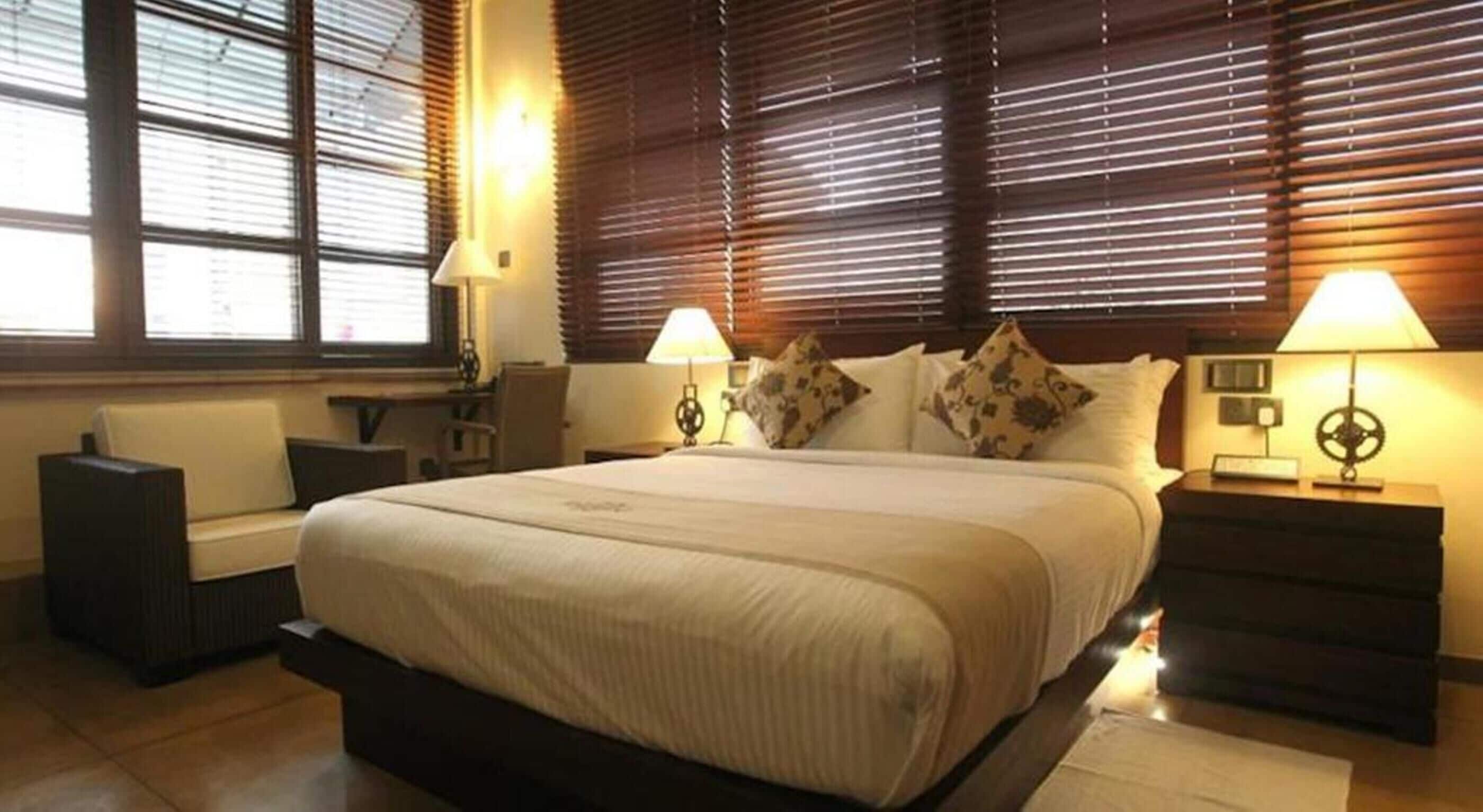A hotel room with a large bed, two bedside tables with lamps, a chair, and a desk.