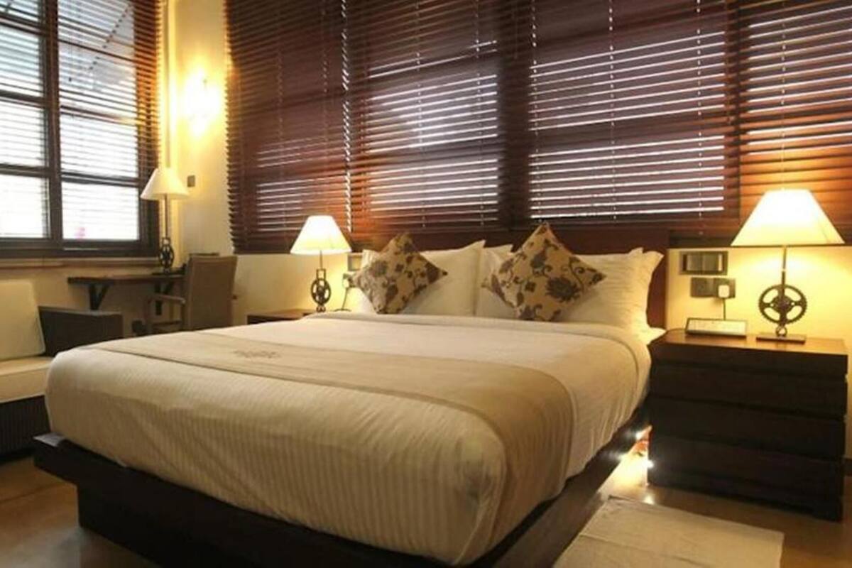 Camera d'albergo con un letto grande, due comodini con lampade, una sedia e una scrivania.