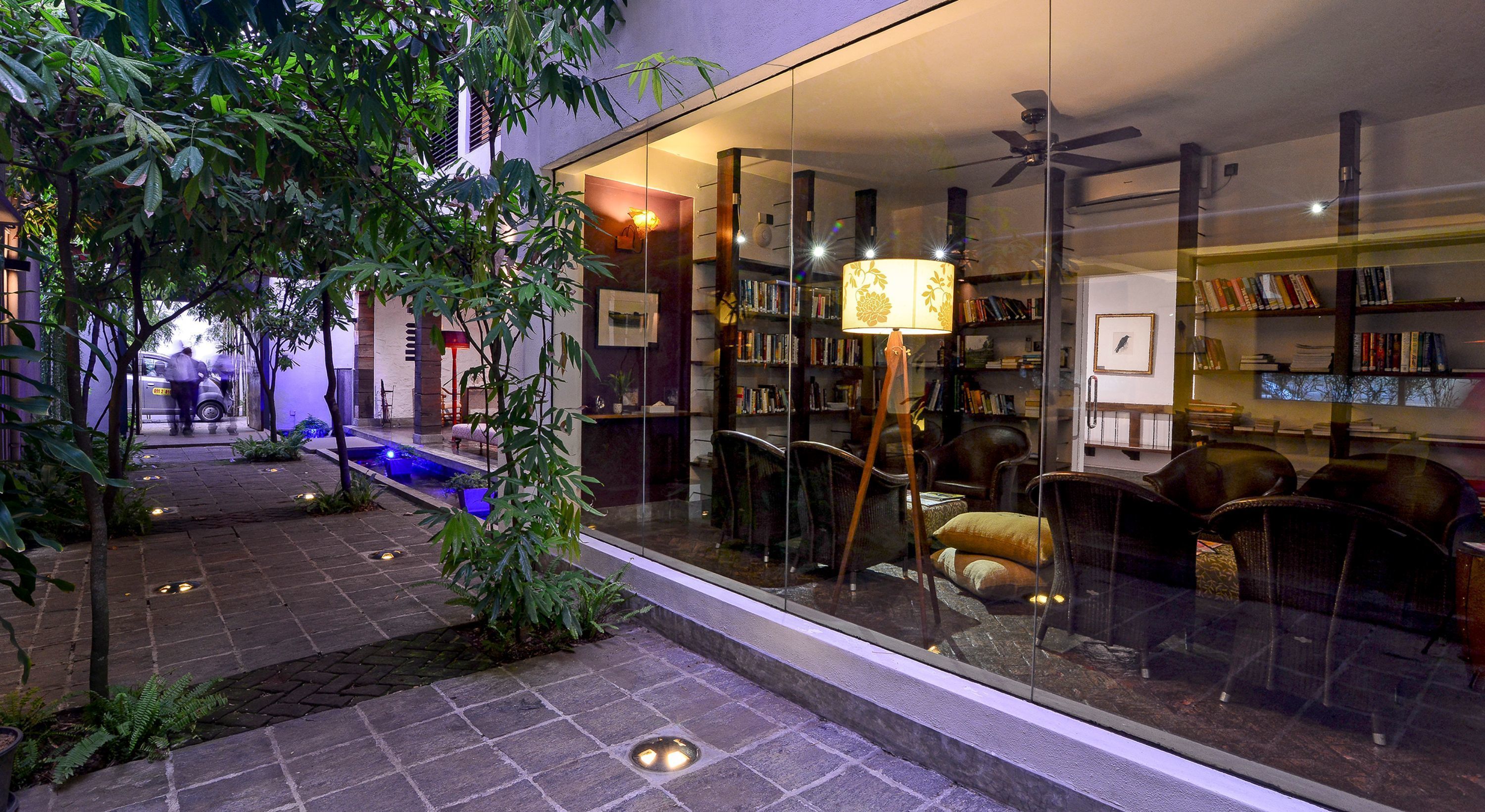 Un jardin intérieur avec un mur de verre, une bibliothèque et un coin salon.