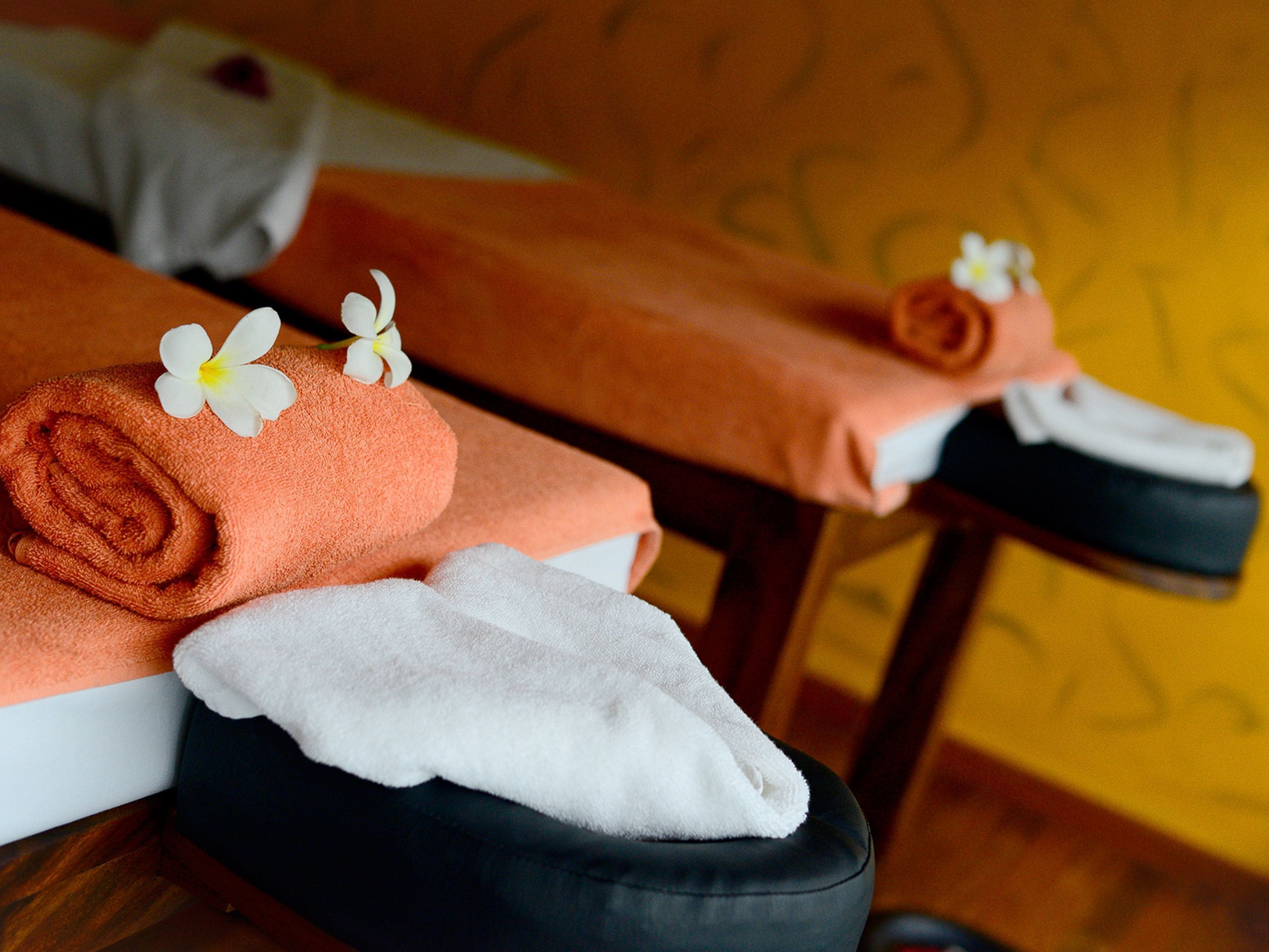 Ein Massagetisch mit Handtüchern und Blumen.