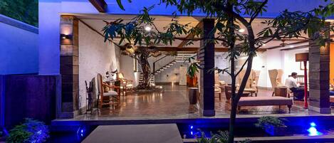 A modern indoor courtyard with a stone floor, a central tree, and seating areas.