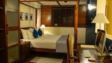 Una cama con dosel de madera, un escritorio con computadora y un ventilador de techo.