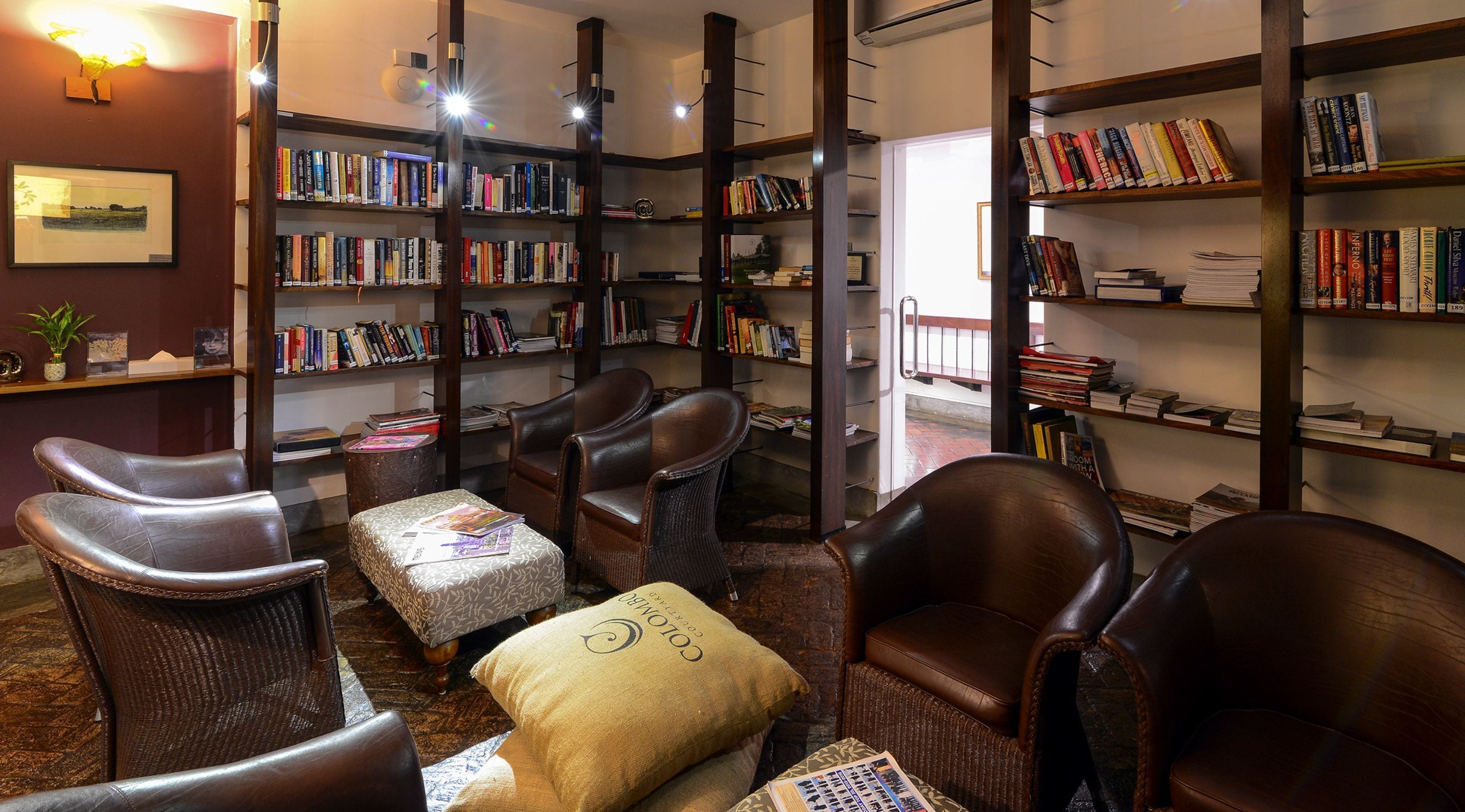 A library with leather chairs, bookshelves, and a fireplace.