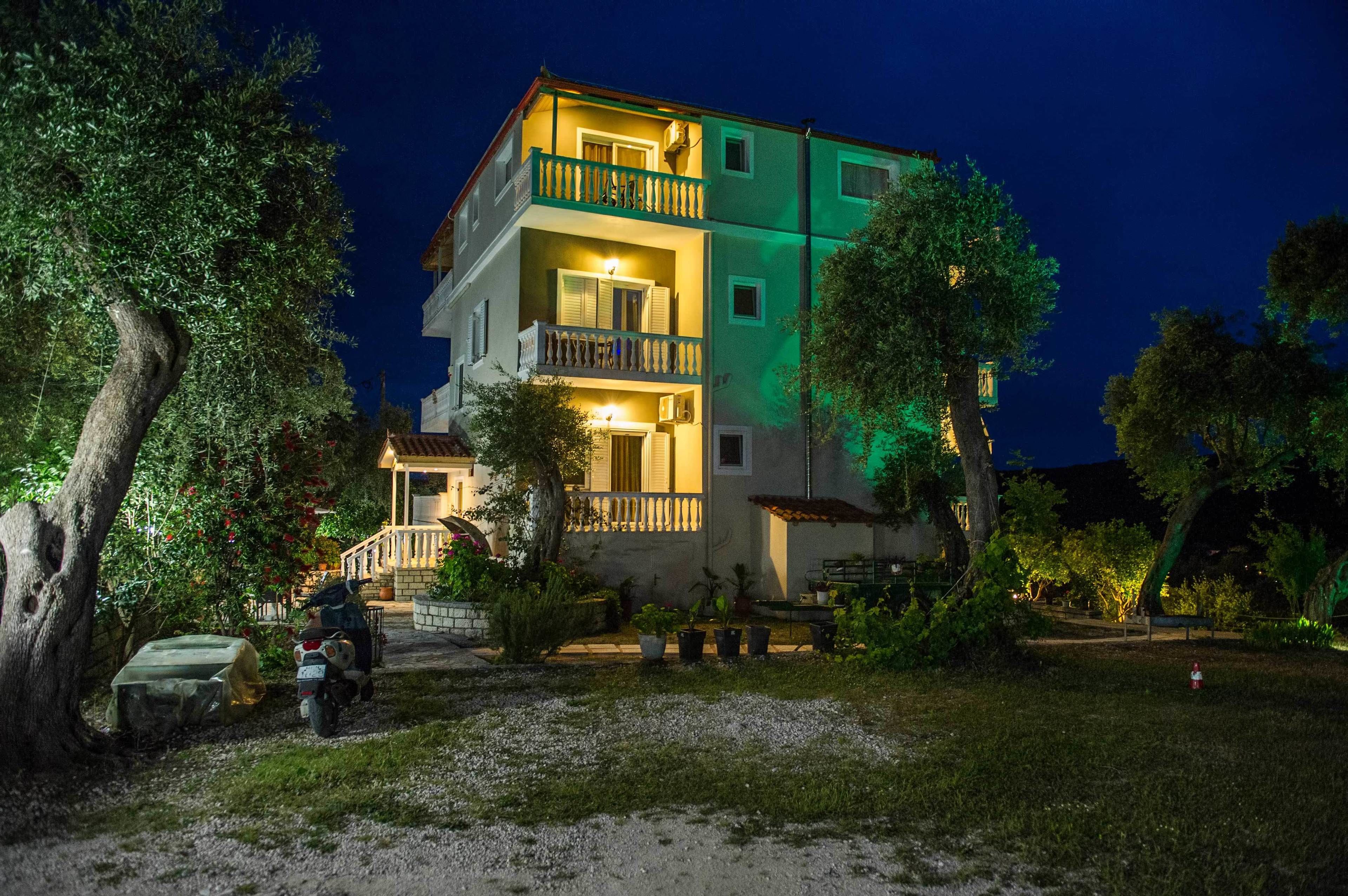A multi-story building with balconies, a covered porch, and a parked scooter.