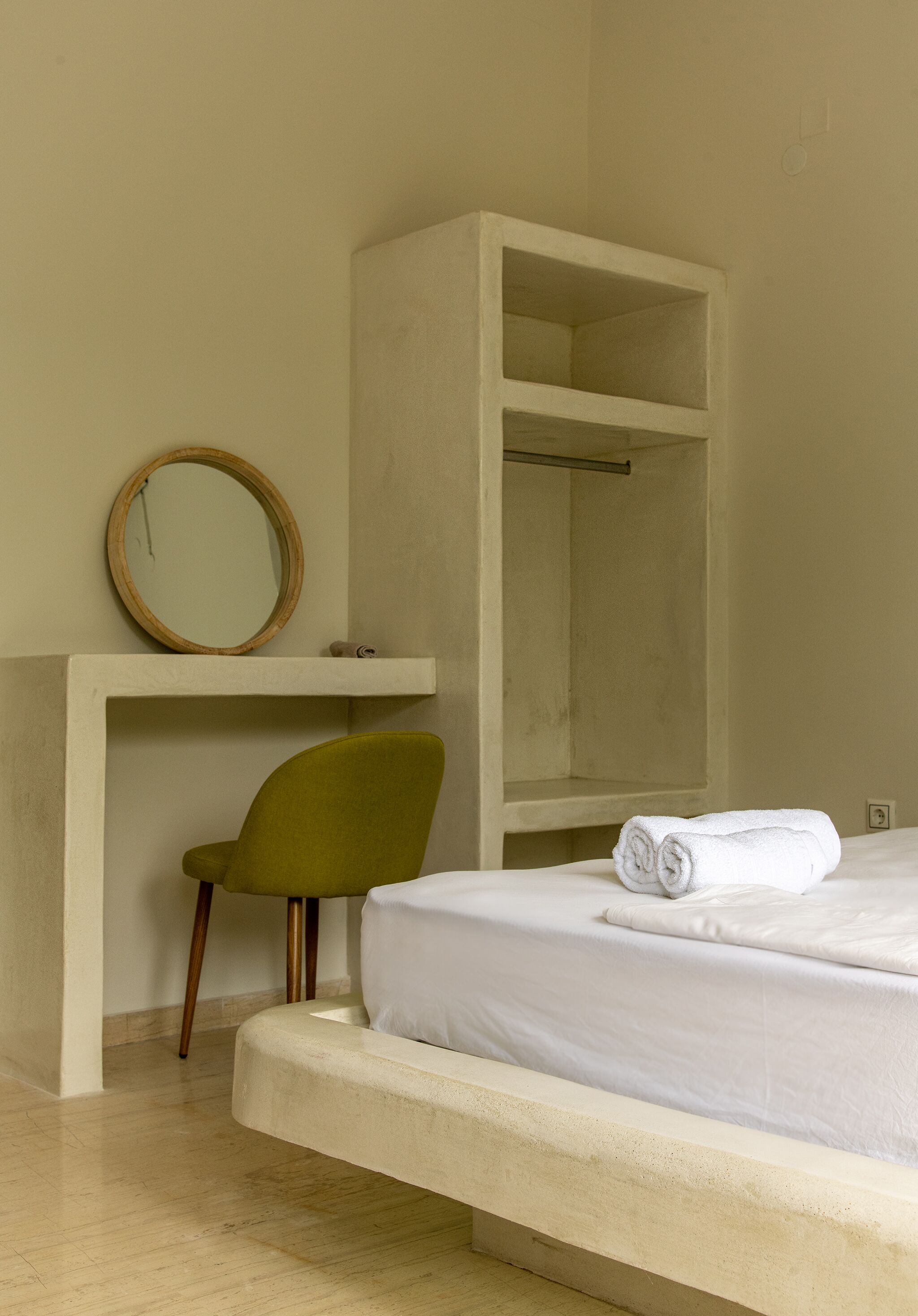Un dormitorio con cama, una silla, un espejo y un armario.