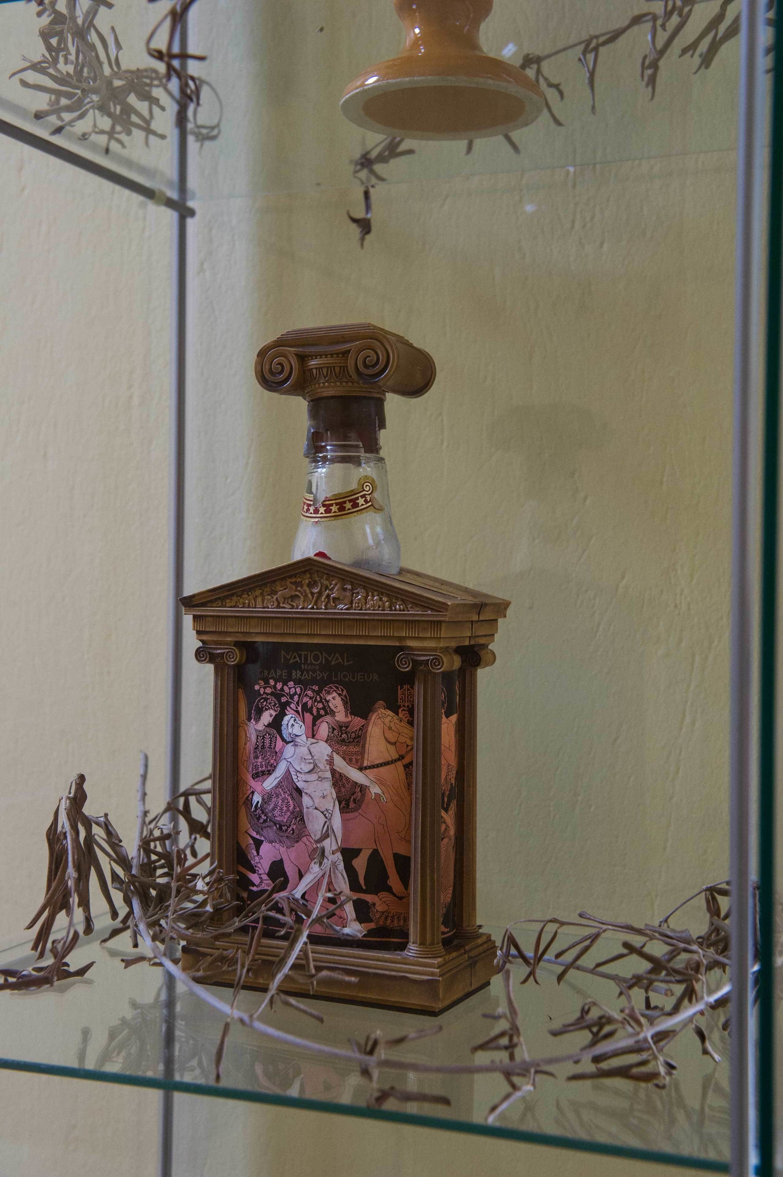 A bottle with a decorative label and a glass enclosure.