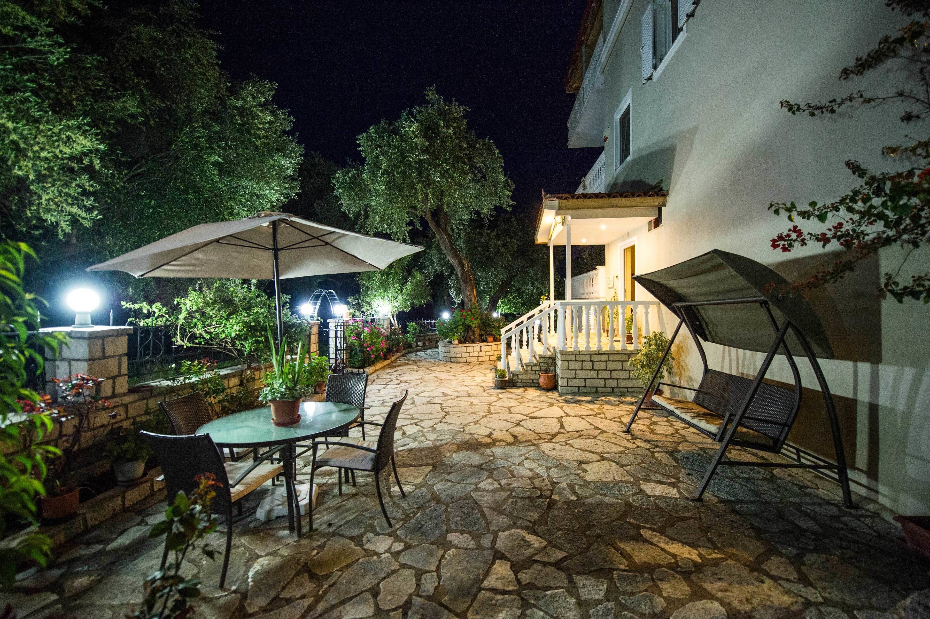 Un patio al aire libre con suelo de piedra, una mesa con sillas y un paraguas grande.