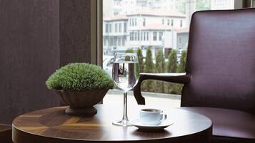 A round wooden table with a potted plant, a glass of water, and a cup of coffee.