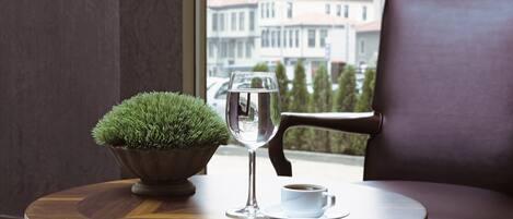 Una mesa de madera redonda con una planta en maceta, un vaso de agua y una taza de café.