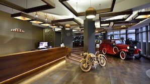 Un área de recepción con un mostrador de madera, una motocicleta antigua y un coche clásico.