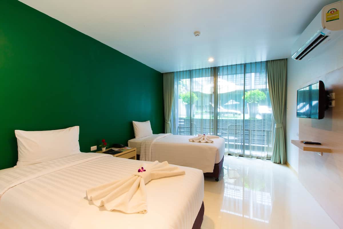 A hotel room with two beds, a TV, and a window with curtains.