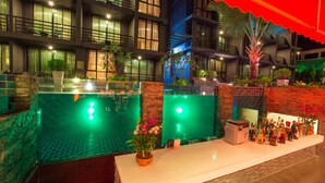 Un espace piscine doté d’un bar et de chaises longues, entouré d’un bâtiment comportant de nombreux balcons et fenêtres.