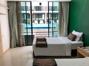 Habitación de hotel con cama, mesita de noche y vista a una piscina.