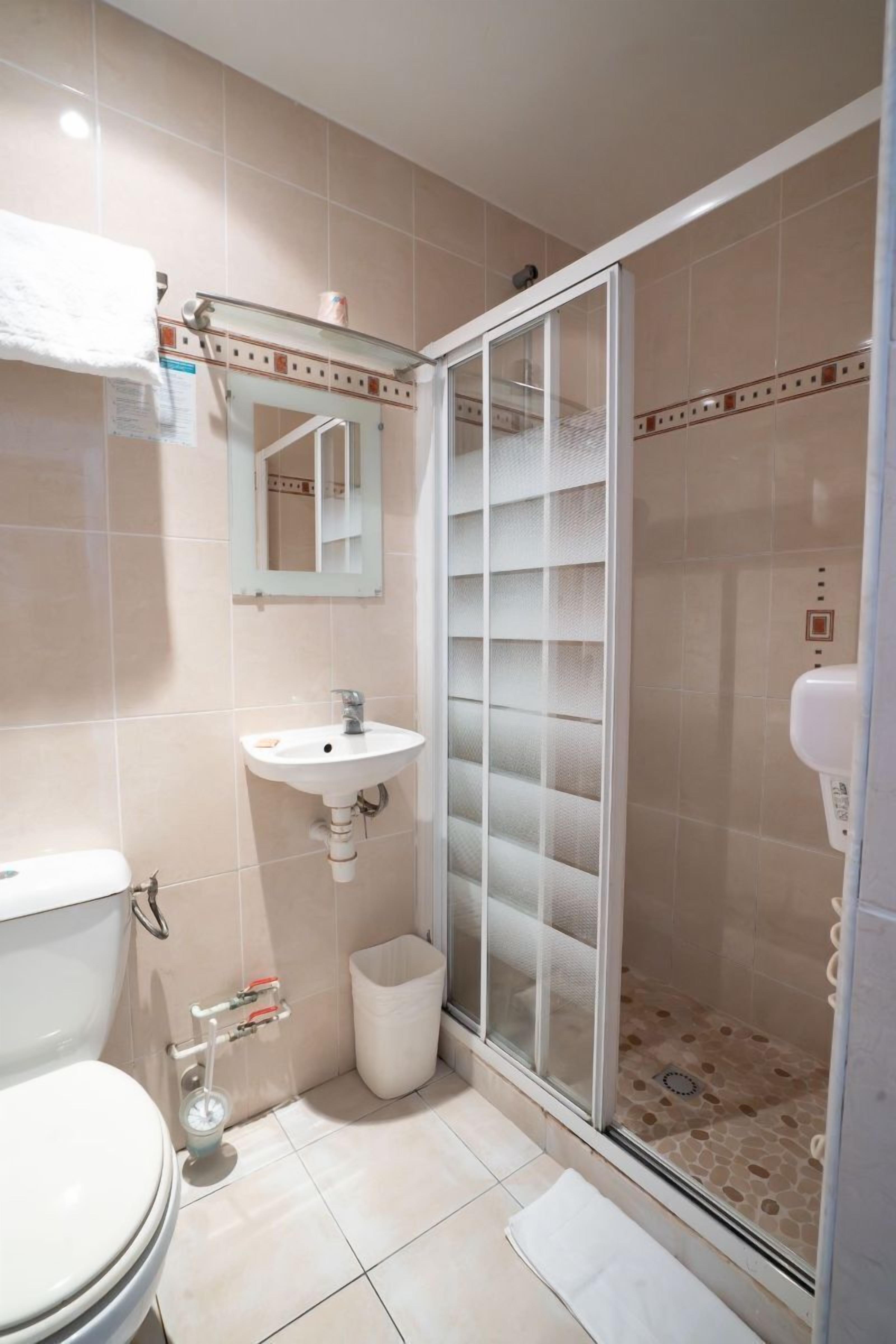 Une salle de bain équipée de toilettes, d’un lavabo et d’une douche à parois en verre.