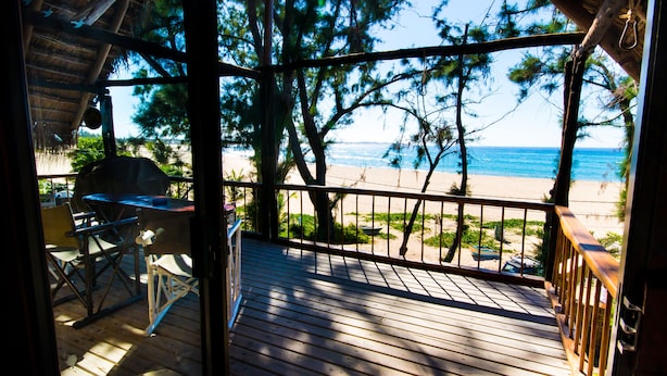 Una terraza de madera con vista a una playa y al océano.