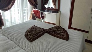 Habitació d'hotel amb llit, escriptori, cadira, televisió i armari.