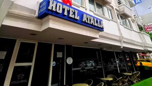 Un hotel de diverses plantes amb balcons, un cartell blau destacat amb la inscripció “Hotel Atalla”, i una zona de restaurant visible amb terrassa.