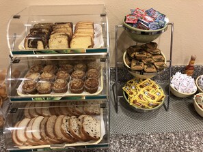 A display of bakery items including bread, muffins, and pastries in a glass case.