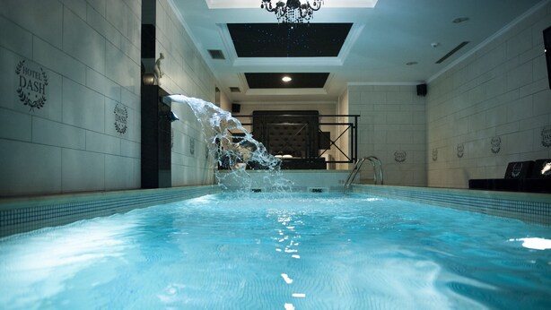 A swimming pool with water jets, a statue, and a chandelier in a hotel setting. - Dash Hotel (Novi Sad)