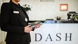 A person holding a device in front of a reception desk with the word "DASH" on it. - Dash Hotel (Novi Sad)