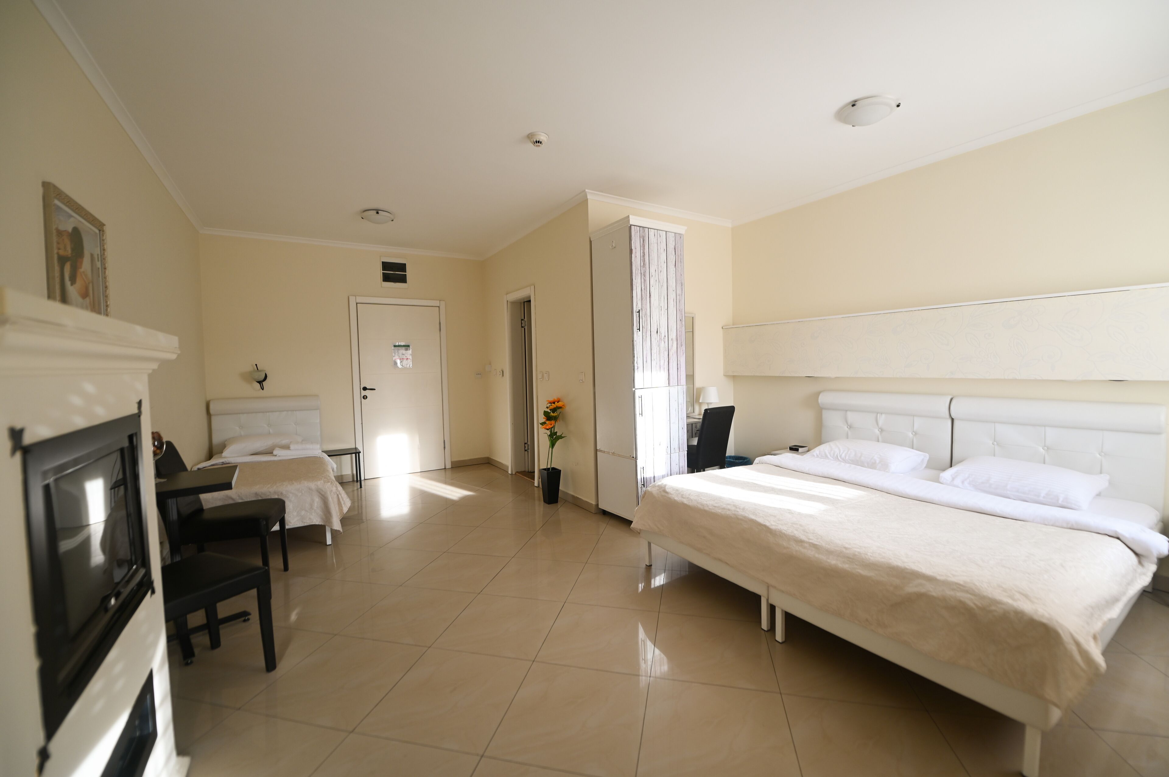 Ein Hotelzimmer mit einem großen Bett, einem Schreibtisch mit Stuhl, einem Kamin und einer Tür zu einem weiteren Raum.