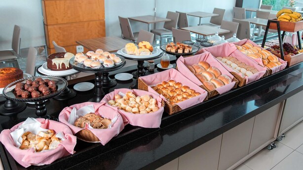 Un bufé con diferentes opciones de comida, incluyendo pasteles, pan y postres.