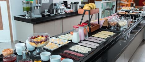 A buffet with various food items, including fruits, cheeses, and meats.
