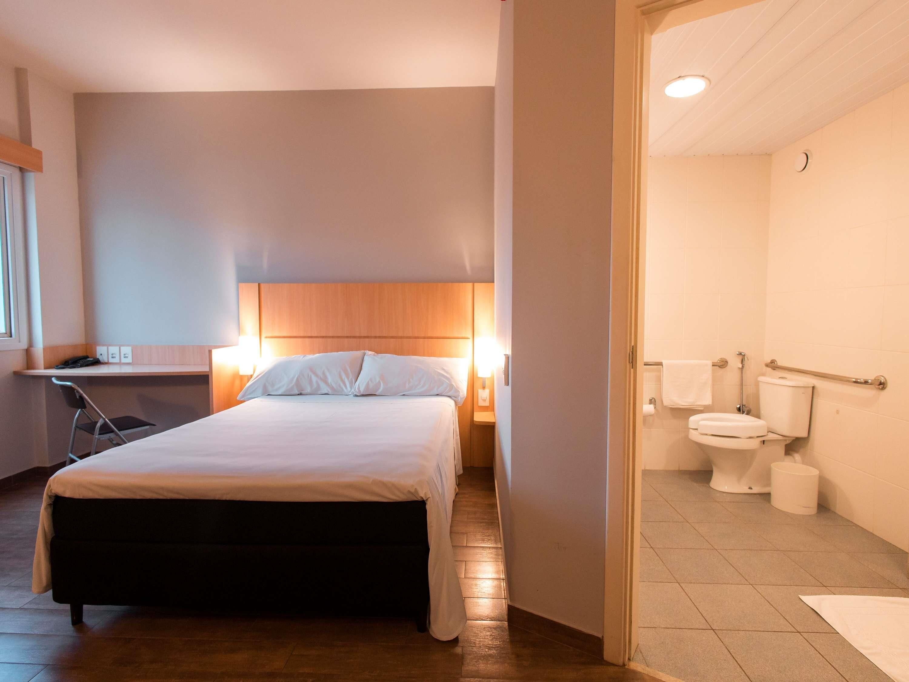Une chambre d’hôtel avec un lit, une table de chevet, une lampe et une vue sur la salle de bain.