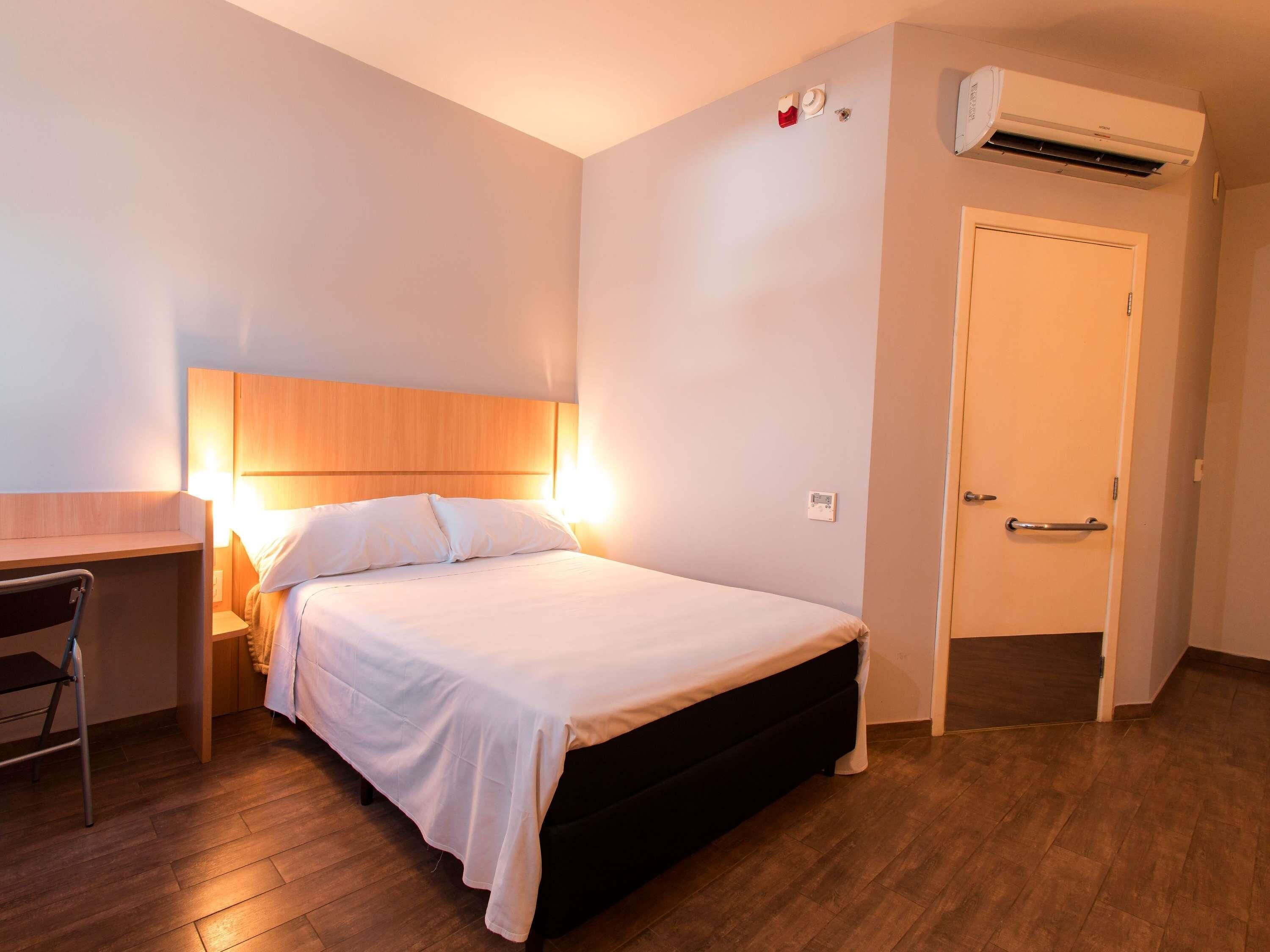 Une chambre d’hôtel équipée d’un lit, d’une table de chevet, d’une chaise et d’un appareil de climatisation.