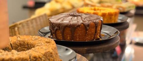 A buffet table with various baked goods, including a chocolate-glazed cake and a fruit-topped cake.