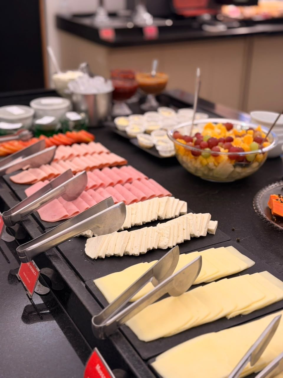 A buffet with various food items including sliced meats and cheeses.