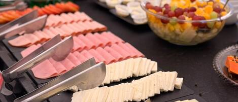 A buffet with various food items including sliced meats and cheeses.