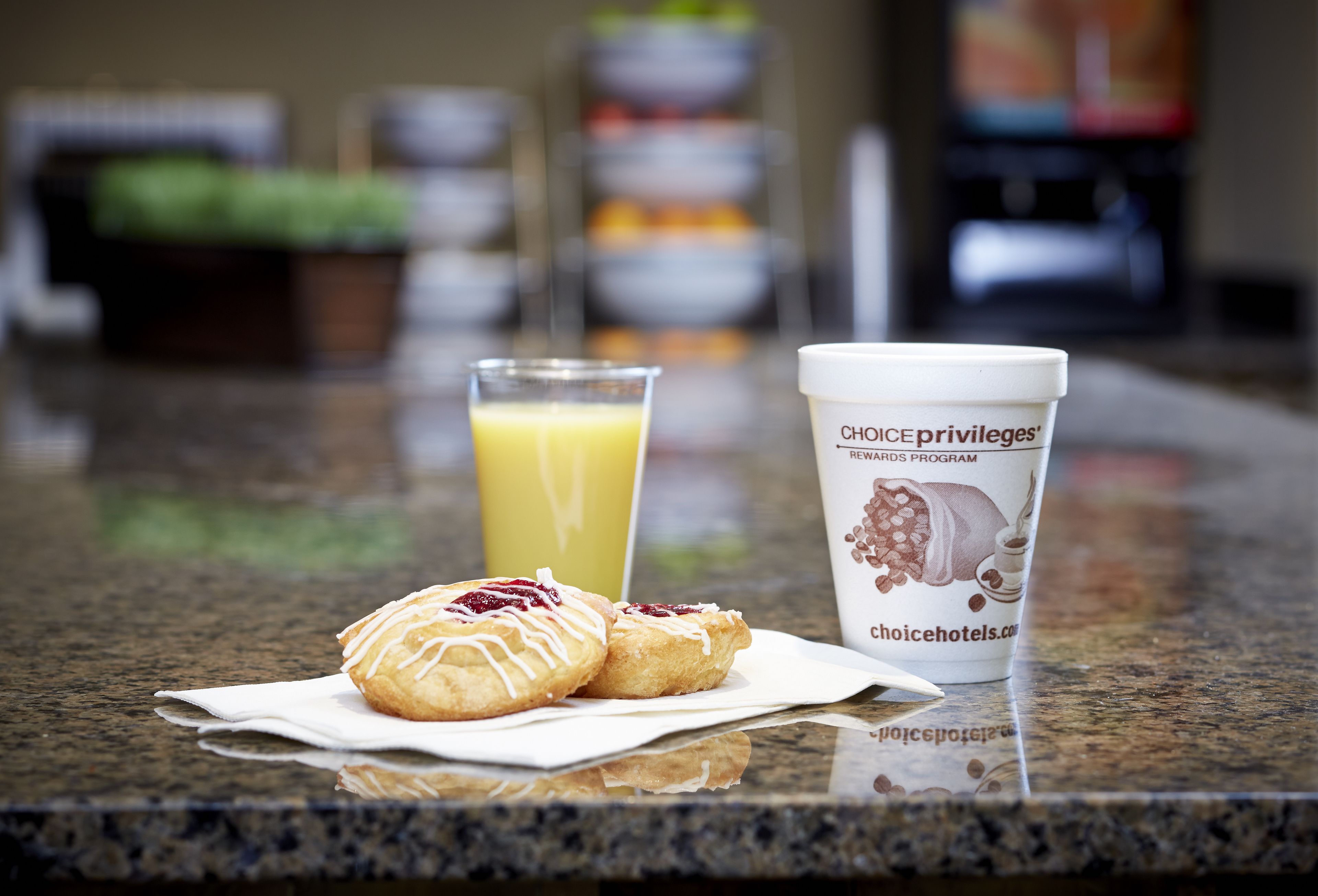 A breakfast setting with pastries and a juice glass on a marble countertop.