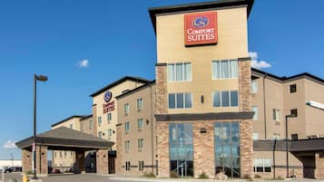 Un hotel Comfort Suites con un diseño moderno, que presenta un letrero llamativo, varios pisos y una zona de estacionamiento cubierta.