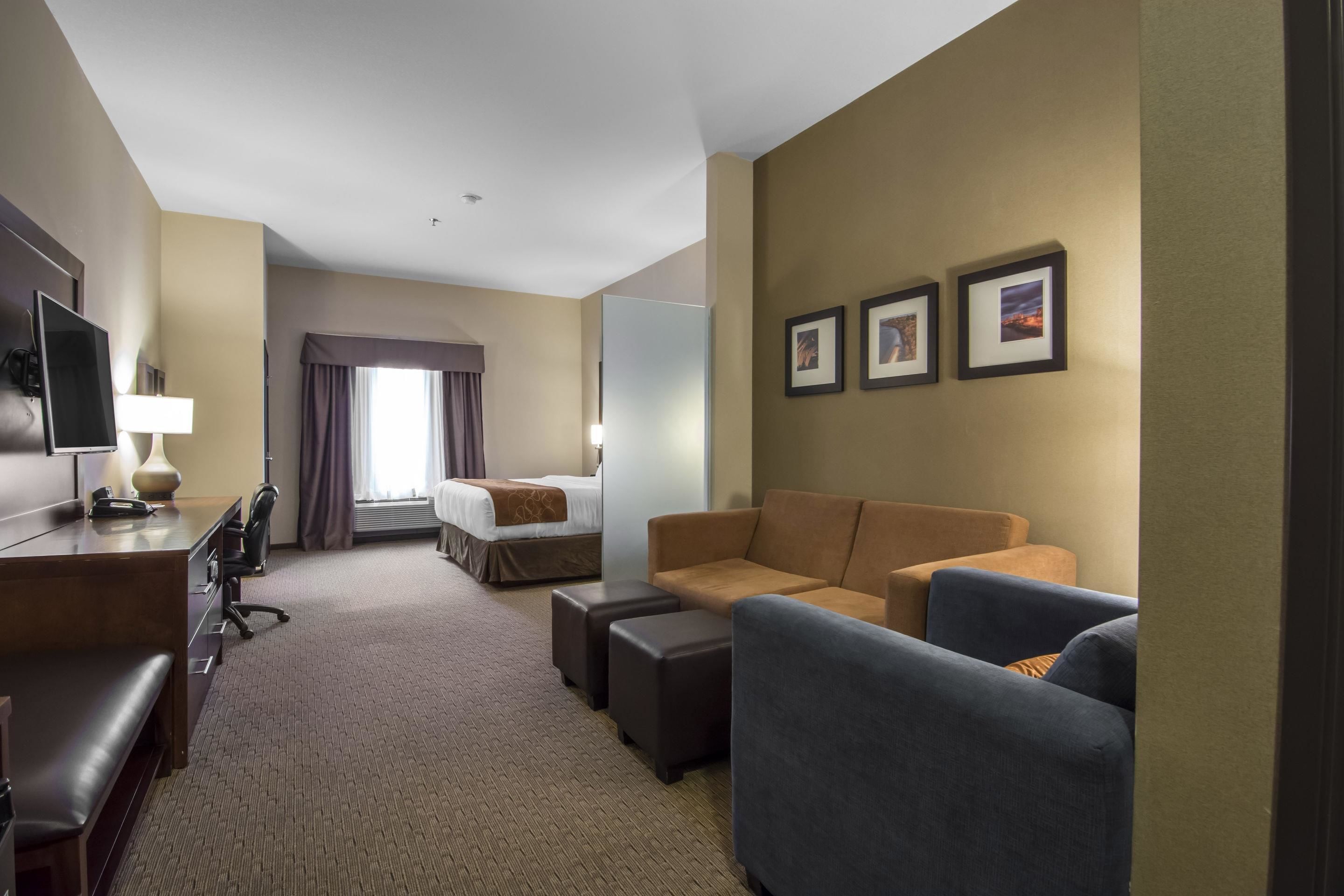 A hotel room with a bed, a desk with a chair, a sofa, and a TV.